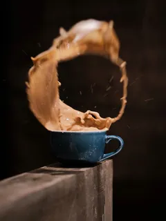 Xícara de café com pedaço de comida em chamas ao fundo